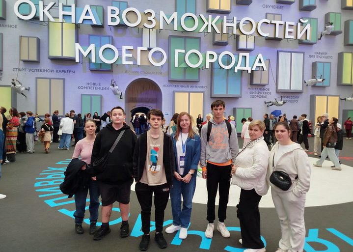 Группа ребят стоят на фоне надписи, которая гласит: Окна возможностей моего города